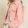 A woman wearing a pink jacket with patches on the back.