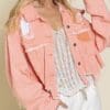 A woman wearing a pink jacket and white pants.