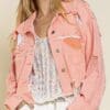 A woman wearing a pink jacket and white pants.