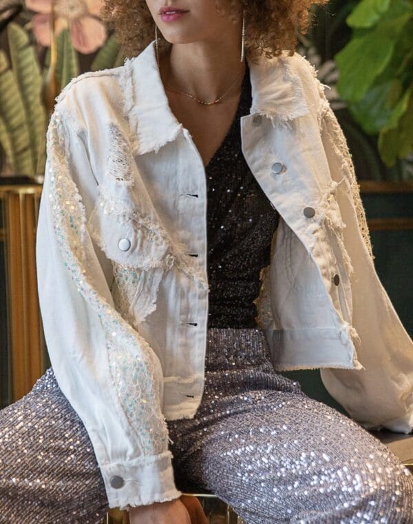 A woman sitting on the ground wearing white jacket.