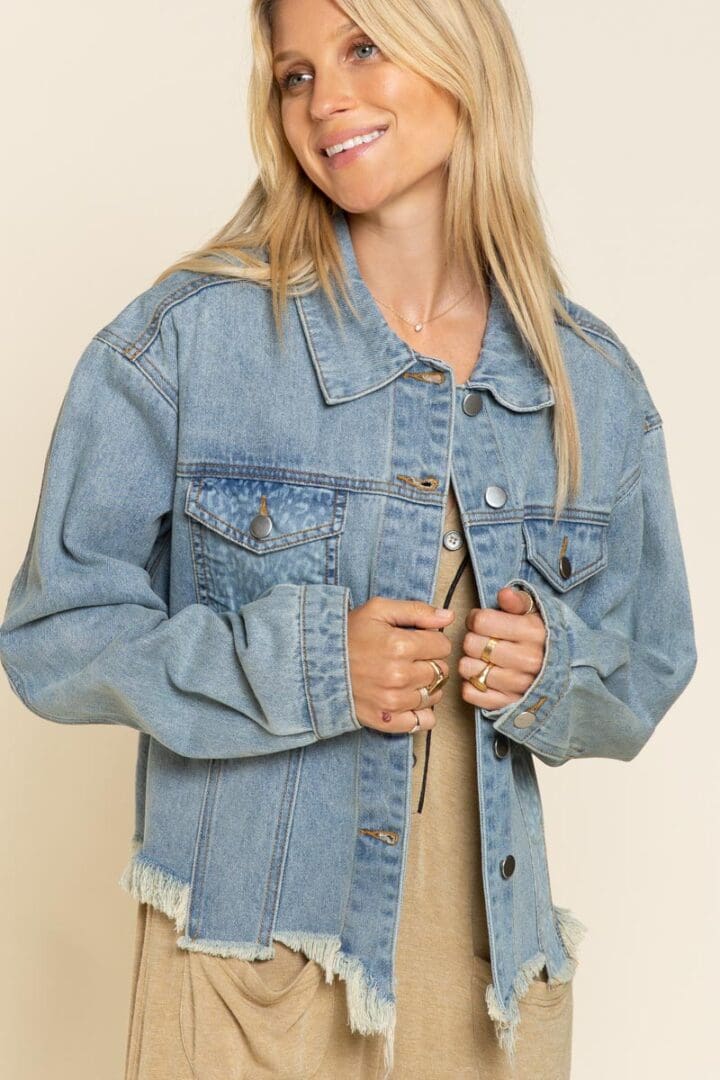 A woman in a jean jacket is holding her shirt open.