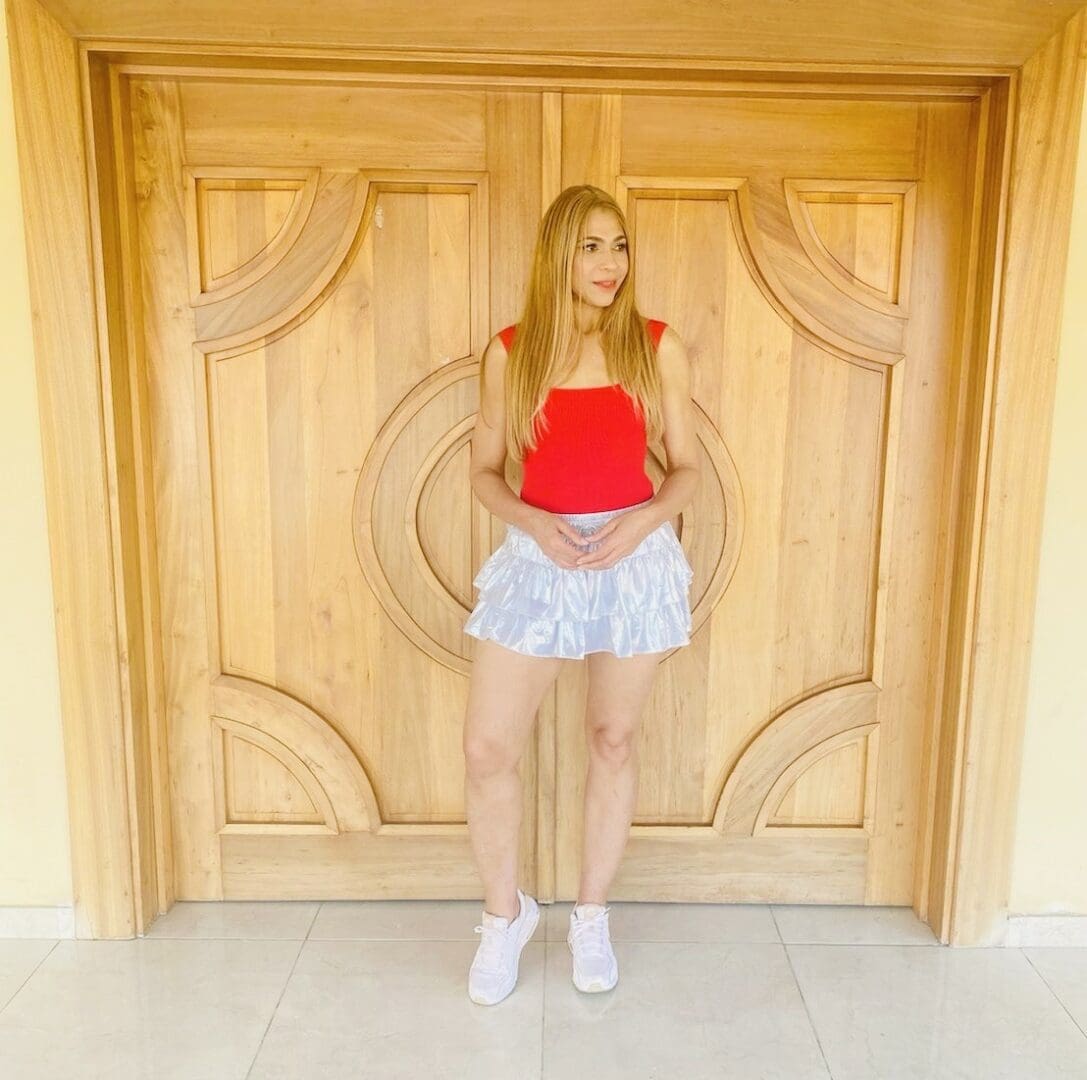 A woman standing in front of a wooden door.