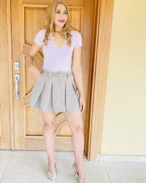 A woman standing in front of a door wearing a skirt.