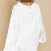 A woman in white robe standing next to wall.