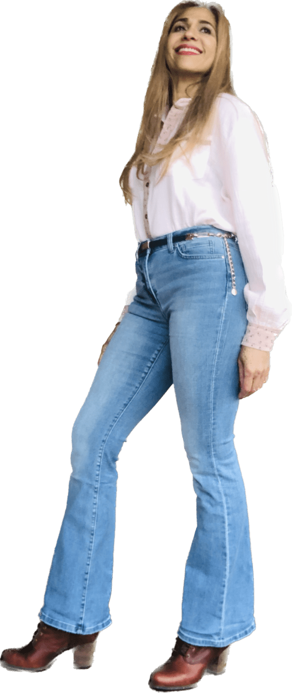 A woman wearing jeans and boots standing in front of a green background.