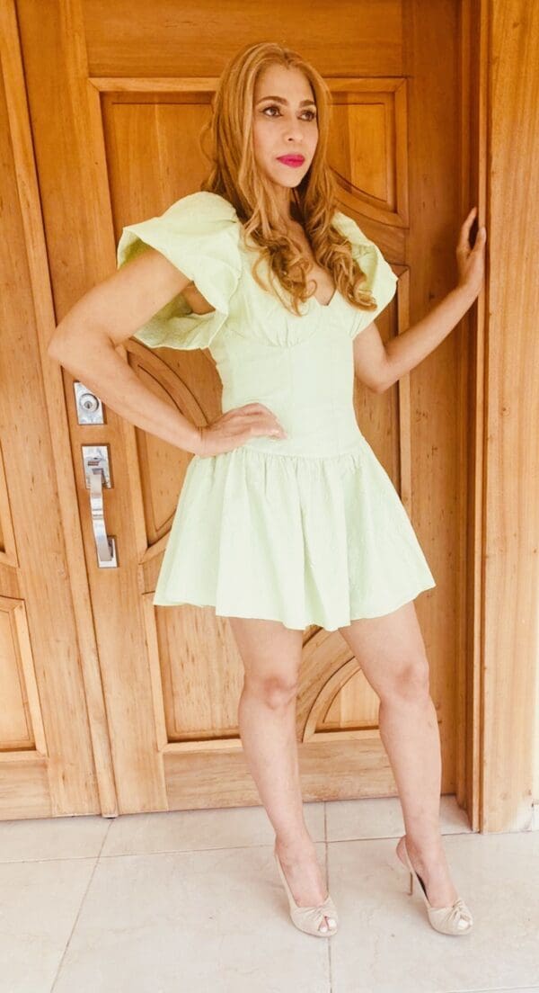 A woman in white dress standing next to a door.