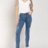 A woman wearing jeans and white shirt standing on one leg.