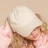 A woman with curly hair wearing a hat.