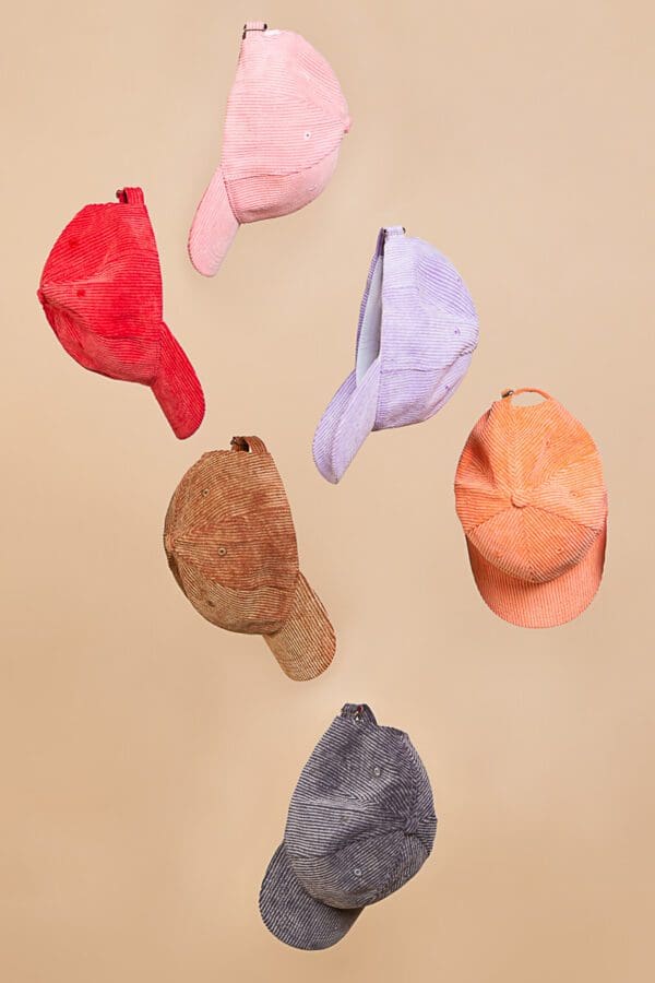 A bunch of different colored hats hanging from the ceiling