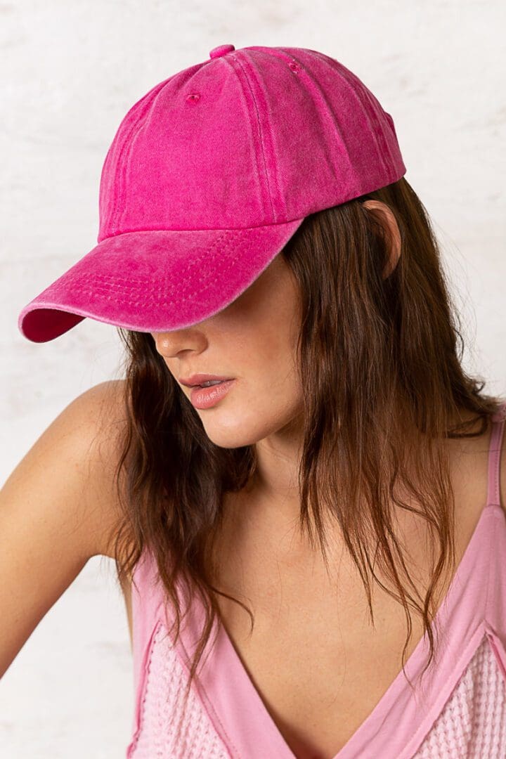 A woman wearing a pink hat and looking down.