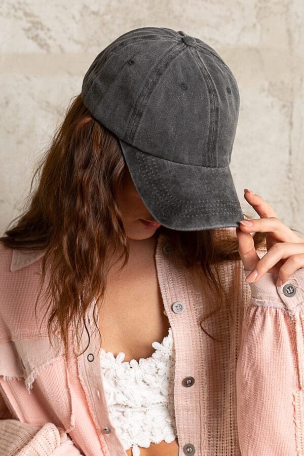 A woman wearing a hat and pink jacket.