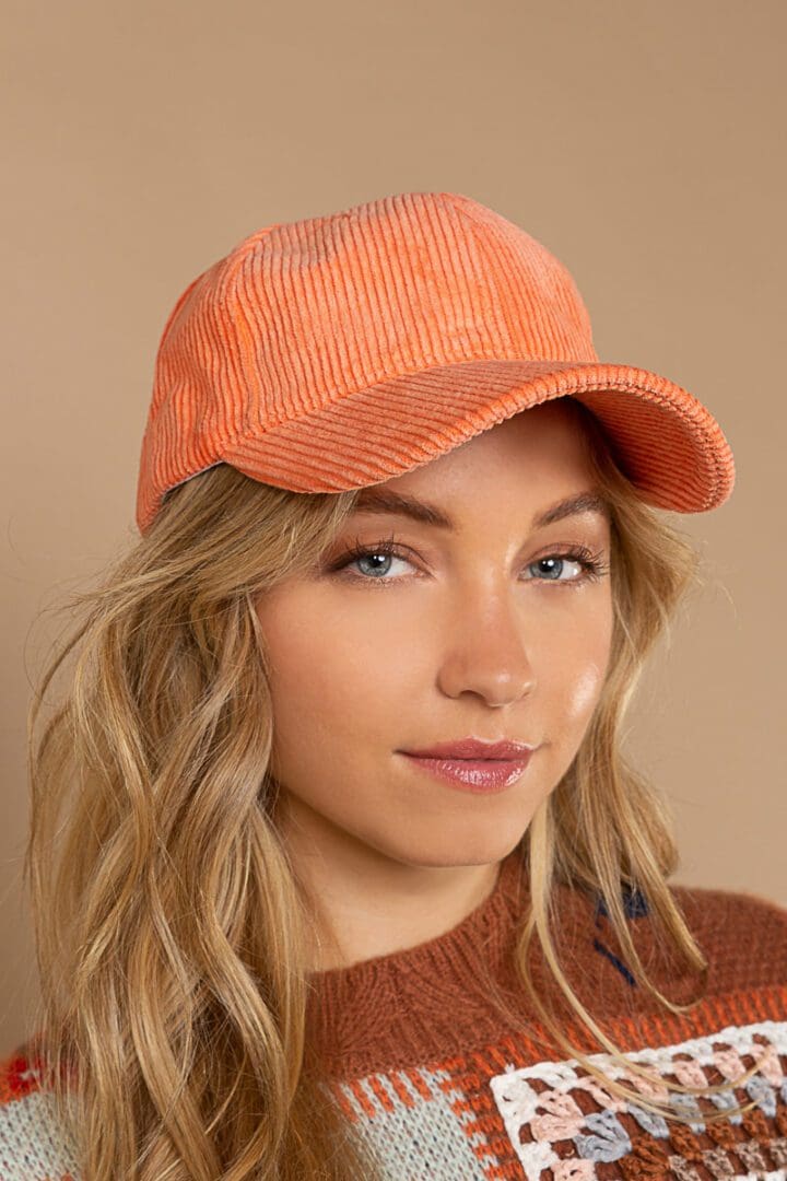 A woman wearing an orange hat and brown sweater.