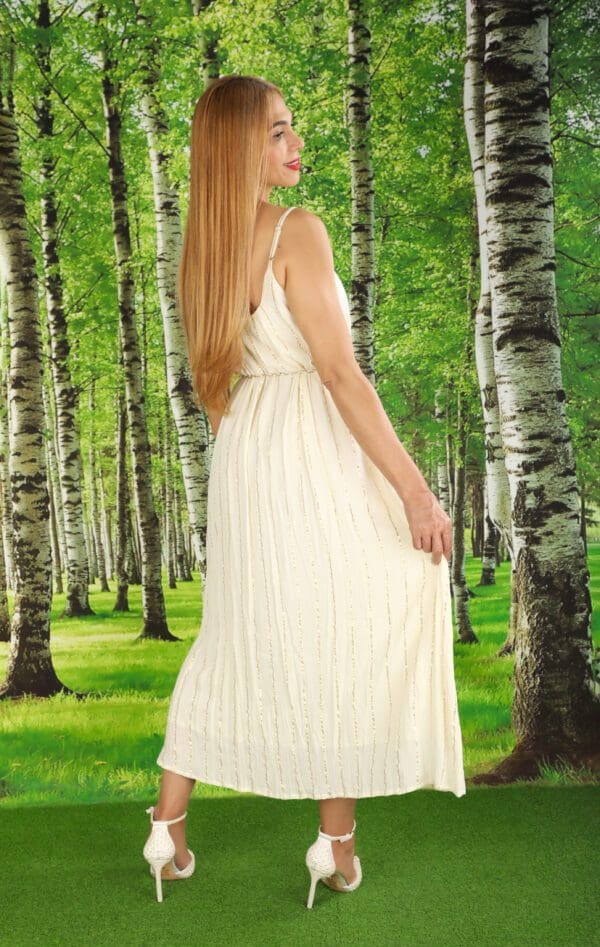 A woman in white dress standing next to trees.