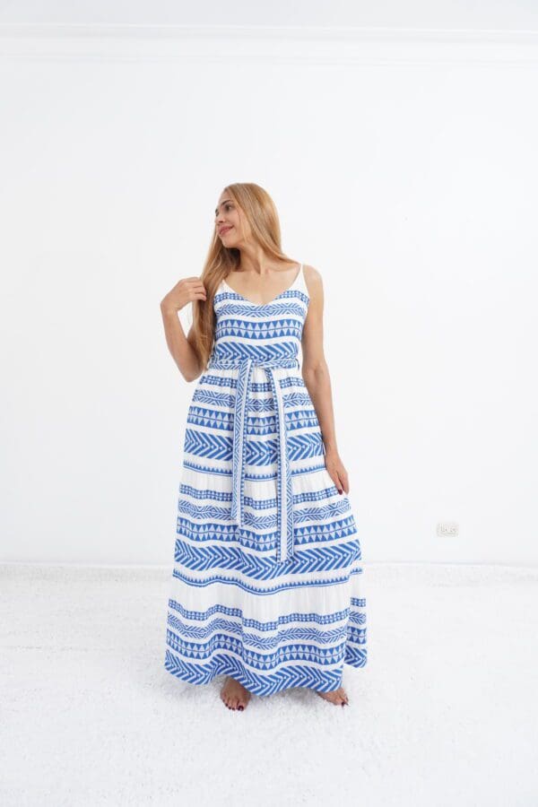 A woman in blue and white dress standing next to wall.