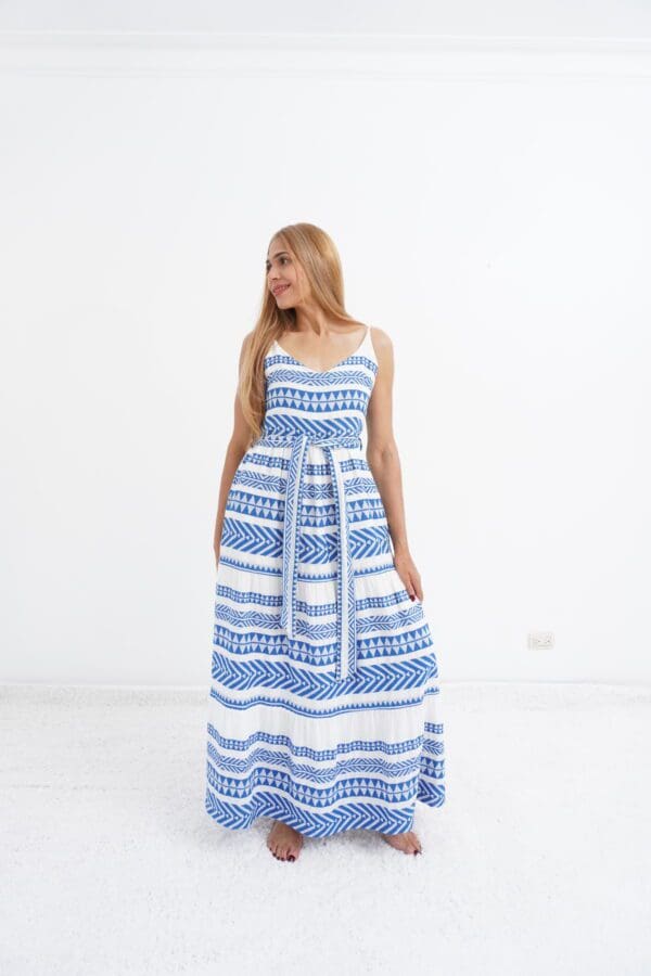 A woman in blue and white dress standing next to wall.