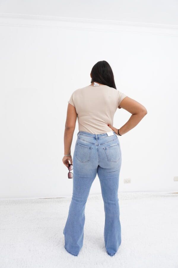 A woman in jeans and a beige shirt holding a can.