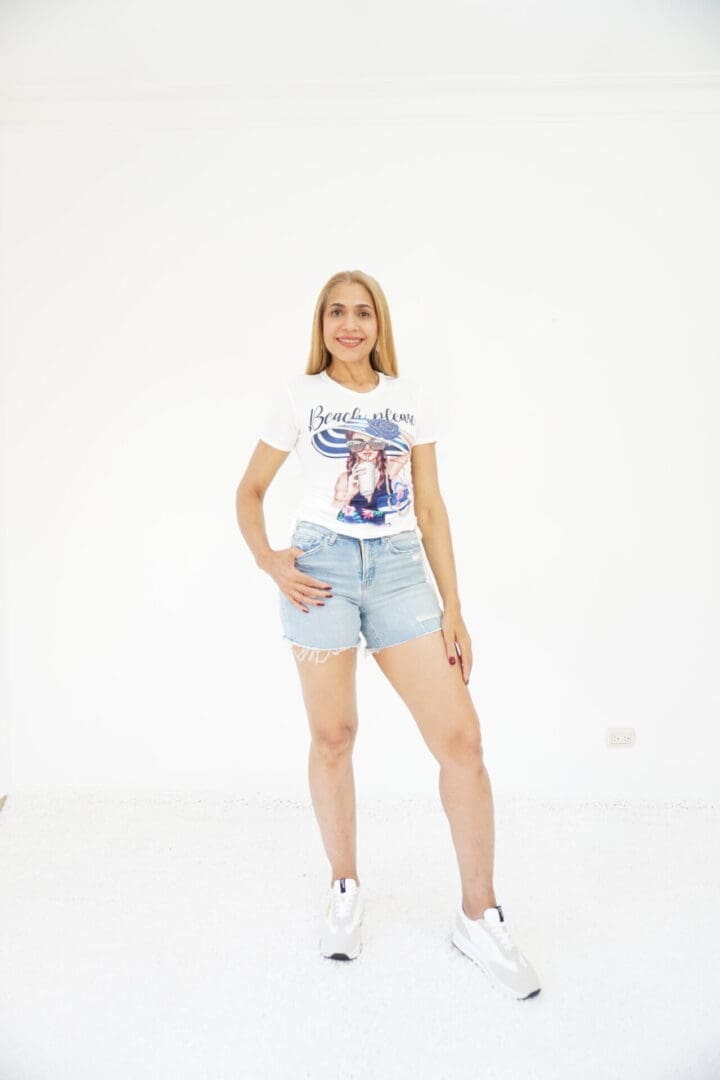 A woman in white shirt and blue shorts standing on one leg.