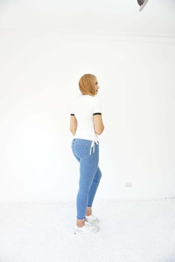 A woman in blue pants and white shirt standing.