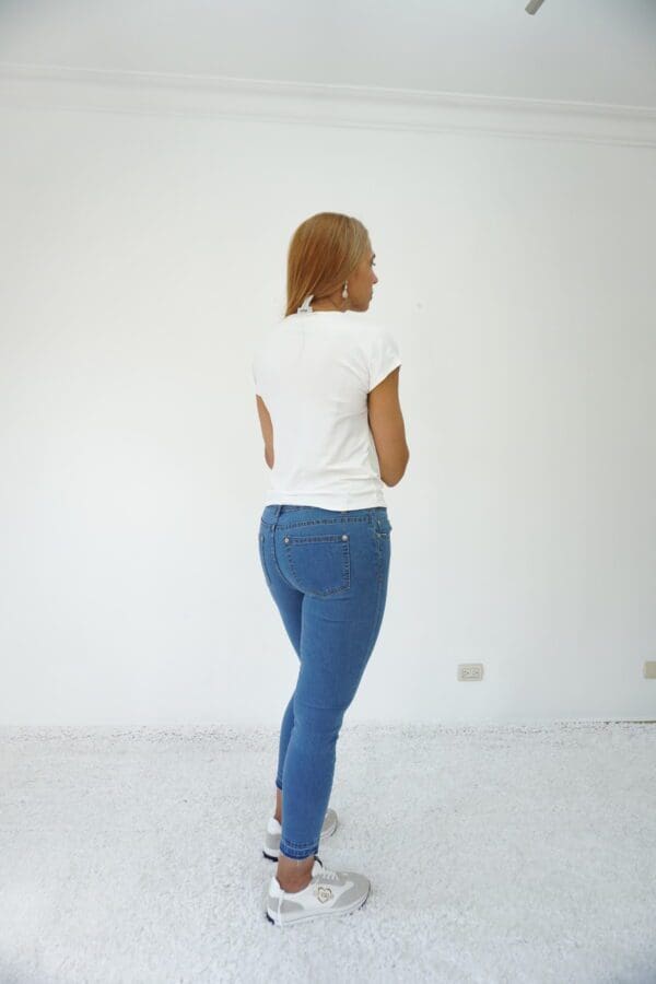 A woman in blue jeans and white shirt standing on the floor.