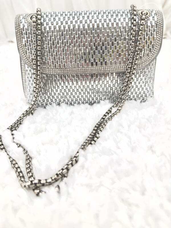 A silver purse sitting on top of white fluffy carpet.