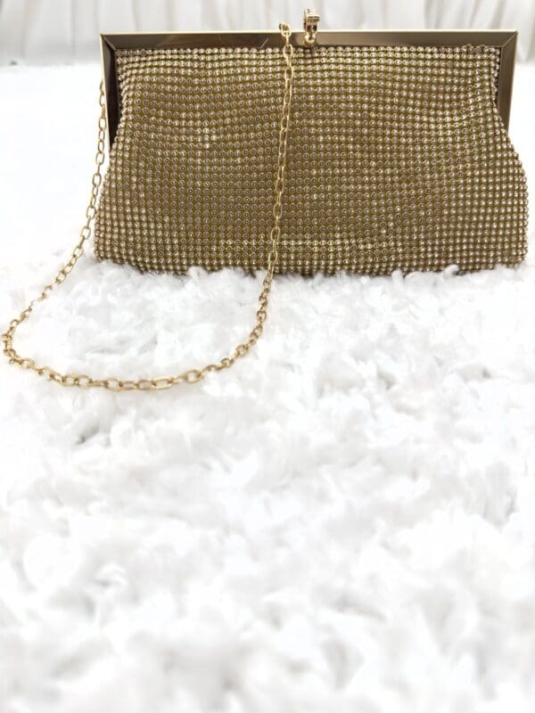 A gold purse sitting on top of white fluffy carpet.