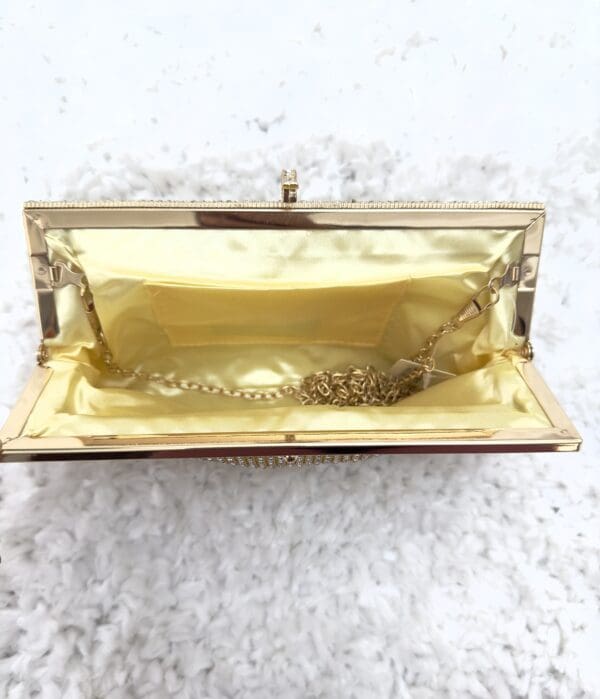 A gold purse sitting on top of a white carpet.