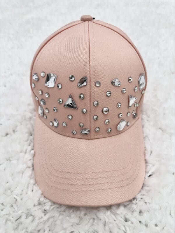 A pink hat with silver and clear stones on it.