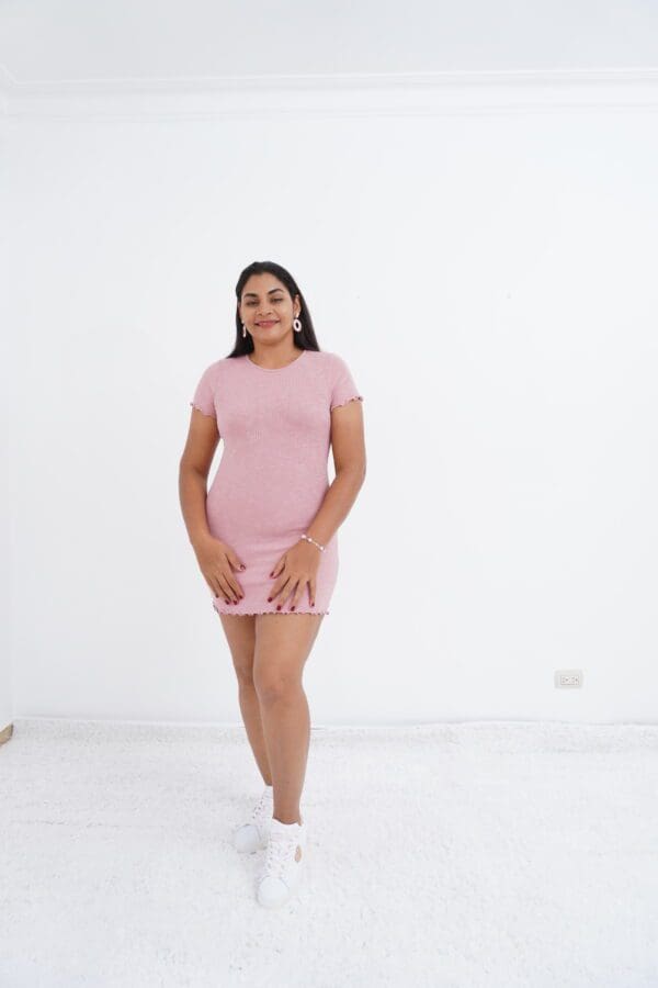 A woman in pink dress standing on white floor.