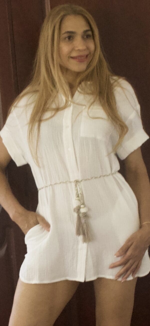 A woman wearing white shirt and belt with tassels.