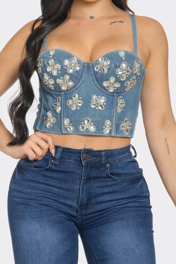 A woman wearing blue jeans and a floral bustier top.