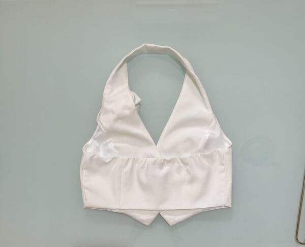 A white halter top is hanging on the wall.