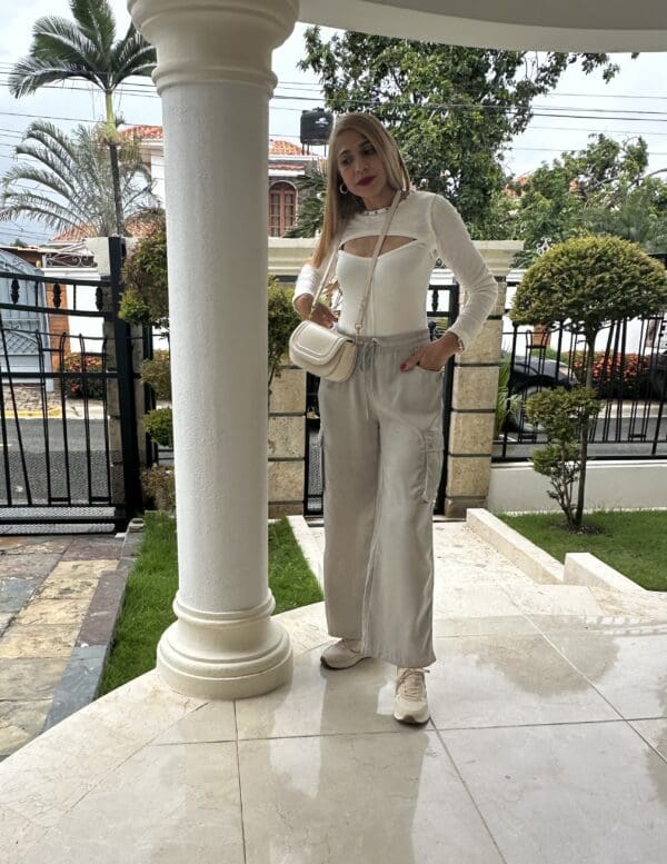 A woman standing in front of a pillar wearing white shoes.