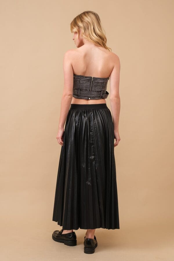 Woman in black pleated maxi skirt and top.