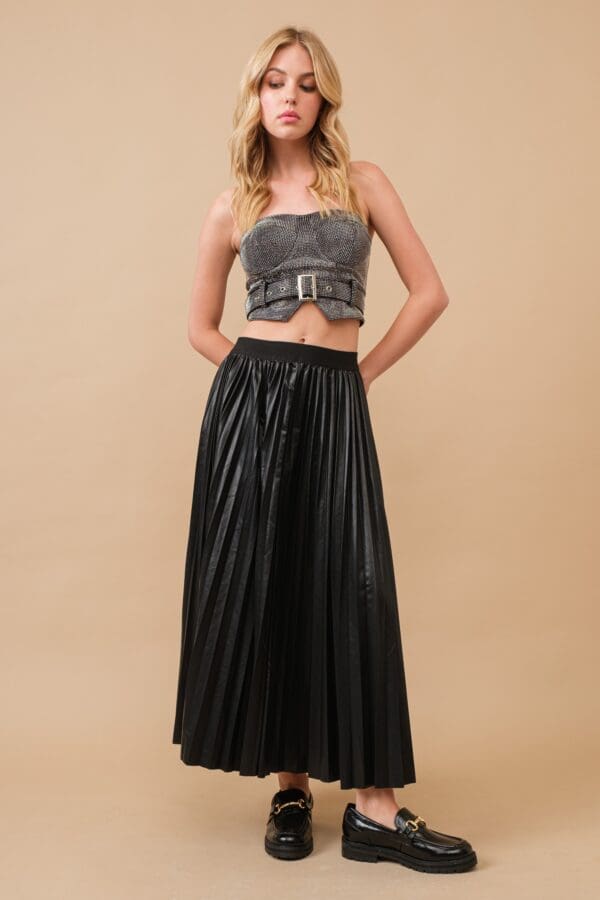 Model in black pleated skirt and top.